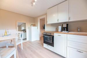 a kitchen with white cabinets and a table and a refrigerator at Landhaus am Meer - Whg 1 Norderaue in Utersum