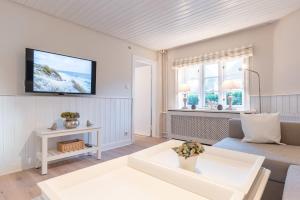 a living room with a couch and a tv on the wall at Landhaus am Meer - Whg 1 Norderaue in Utersum