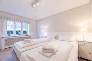 a white bedroom with two beds and a window at Landhaus am Meer - Whg 1 Norderaue in Utersum