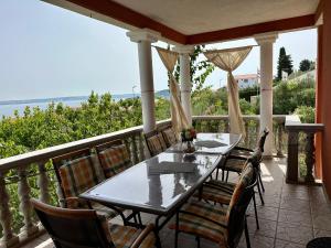 a table and chairs on a porch with the ocean at Duplex Apartment with Private Swimming Pool in Preko