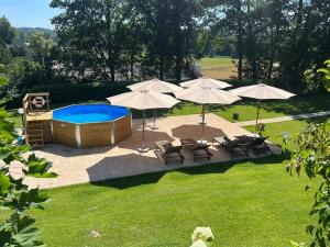 a backyard with a pool and umbrellas and chairs at Landhaus Finest Haus Weickenhof in Velburg