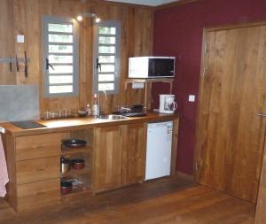 uma cozinha com armários de madeira e um frigorífico branco em bambous-bungalows em Entre-Deux