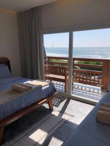 1 dormitorio con 2 camas y vistas al océano en Pousada Casa Albatross, en Penha