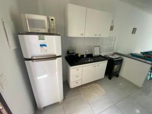 a small kitchen with a refrigerator and a microwave at Mahalo Beach Residence in Porto De Galinhas