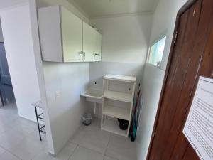 a small white bathroom with a sink and cabinets at Mahalo Beach Residence in Porto De Galinhas