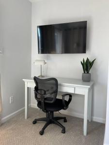 a desk with a chair and a television on a wall at Oceanview Townhouse w/ Pool - Newly Renovated in Surf City