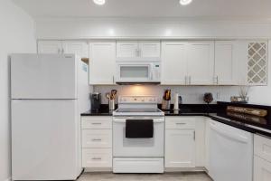a kitchen with white cabinets and a white refrigerator at Oceanview Townhouse w/ Pool - Newly Renovated in Surf City