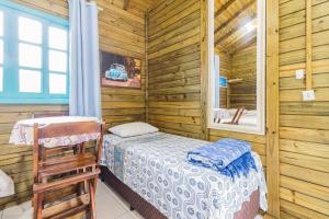 1 dormitorio con 1 cama en una cabaña de madera en Jajá Cabanas, en Palhoça