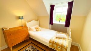 a bedroom with a bed with a dresser and a window at Catcune Family Suite in Gorebridge