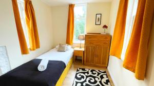 a bedroom with two beds and a window with orange curtains at Catcune Family Suite in Gorebridge