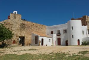 un vieux bâtiment en briques avec deux tours à côté dans l'établissement Casa de Sines, à Sines