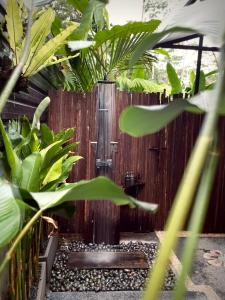a wooden fence with a water fountain in a garden at Kabinji Bali in Tampaksiring