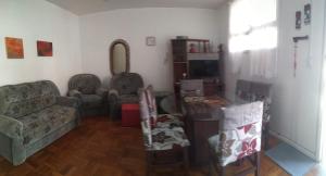 a living room with a couch and chairs and a tv at Apartamento 3 minutos da orla in Capão da Canoa