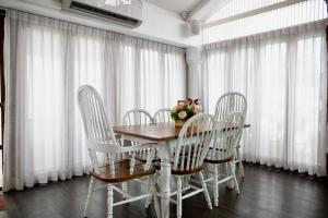 a dining room table and chairs with white curtains at Unique Lanna Style Spa Pool Villa in Chiang Mai