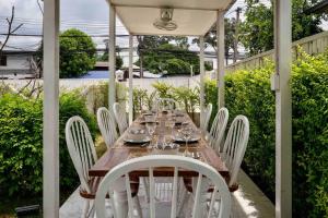 a wooden table and white chairs on a patio at Unique Lanna Style Spa Pool Villa in Chiang Mai