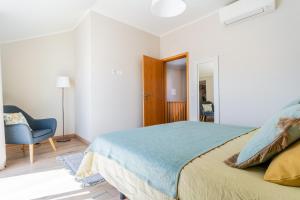 a white bedroom with a bed and a blue chair at Windmill Escape - Onda Townhouse in Odeceixe