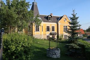 a yellow house with a tree in front of it at Völgy-ucca Apartman in Balatonfüred