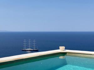 a boat in the water next to a swimming pool at Apartment at KiVA-villa, Kampi, KEA, Cyclades, Greece in Ligia