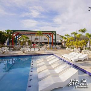 a swimming pool with white chairs and a roller coaster at Caldas Novas - Diroma Fiori - Incluso Parque 24 Horas - Com roupas de cama Incluso in Caldas Novas