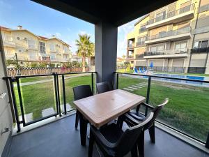 ベレキにあるİris Apartment Belek A1のバルコニー(テーブル、椅子付)、大きな窓が備わります。