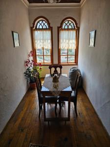 ein Esszimmer mit einem Tisch, Stühlen und Fenstern in der Unterkunft Guest House Panorama in Berat