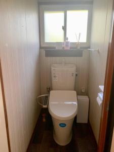 a small bathroom with a toilet and a window at 一棟貸宿　奥入瀬屋 in Yakeyama