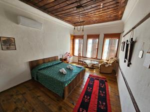 a bedroom with a green bed and a living room at Guest House Panorama in Berat