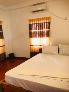 a bedroom with a white bed with a window at Villa Moon breeze Nilaveli in Trincomalee