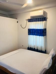 a bed in a room with a blue and white curtain at Villa Moon breeze Nilaveli in Trincomalee