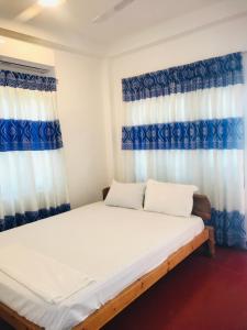 Cama en habitación con cortinas azules y blancas en Villa Moon breeze Nilaveli, en Trincomalee