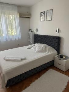 1 dormitorio con 1 cama grande y cabecero negro en White M, en Karaburma