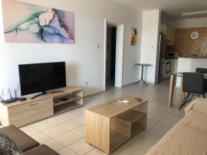 Una sala de estar con un televisor de pantalla plana y una mesa. en Kings Palace - spacious 2-bed with sea views and large patio, en Pafos