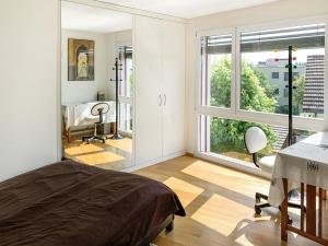 a bedroom with a bed and a desk and windows at Haus zur Lilie in Hinwil