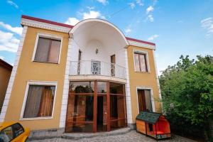 ein gelbes und weißes Haus mit einem Balkon in der Unterkunft Ivertubani House in Tbilisi City