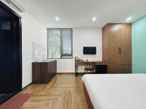 una camera con letto, scrivania e TV di Là Nhà Homestay Huế a Thôn Dương Xuân Hạ