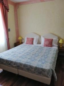 a bedroom with a large bed with pink pillows at Albergo Stella Alpina in Molveno