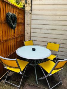 a white table and four yellow chairs next to a fence at Fox hill view in Parkstone