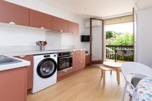 a kitchen with a washing machine and a table with chairs at Le Balcon du Port - Joli studio à Capbreton in Capbreton