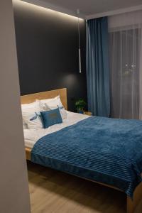 a bedroom with a bed with a blue blanket at Apartament Aleksandra SPA Dziwnów in Dziwnów