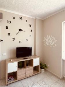 Habitación con TV y reloj en la pared. en Casa vacanze il fiore di loto, en Zibido San Giacomo