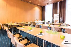 a conference room with tables and chairs and a podium at elaya hotel wolfenbuettel ehemals Rilano 24 7 Hotel Wolfenbüttel in Wolfenbüttel