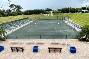 um campo de ténis com bancos e uma raquete de ténis em Awesome Apartment near the Beach em Naples