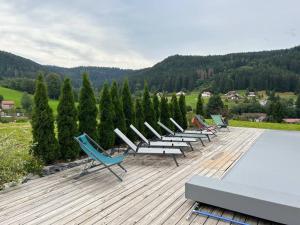 una fila de sillas sentadas en una terraza con piscina en Villa 4 Saisons, avec piscine chauffée et jacuzzi en Gérardmer