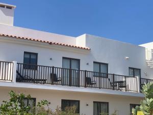 a white building with chairs on a balcony at Salisland365 Private Apartment - Self Catering Dunas Beach Resort in Santa Maria