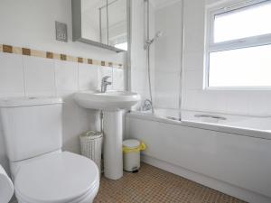 a white bathroom with a toilet and a sink at The Hideaway in Bridport +17 photos