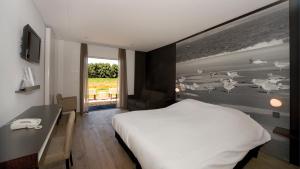 a bedroom with a white bed and a desk and a window at Fletcher Landgoedhotel Renesse in Renesse +47 photos