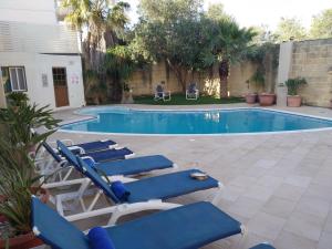 a swimming pool with lounge chairs next to a building at Malta Villa in Naxxar