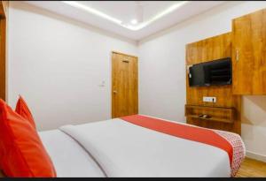 1 dormitorio con 1 cama blanca y TV en la pared en HOTEL SAFARI INN, en Ahmedabad