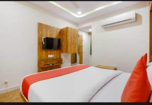 1 dormitorio con 1 cama blanca y TV en HOTEL SAFARI INN, en Ahmedabad