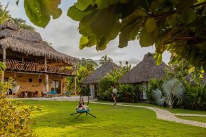 a woman sitting in a hammock in the yard of a resort at Amaca Beach Hotel - Eco Resort Quiimixto in Qumiste